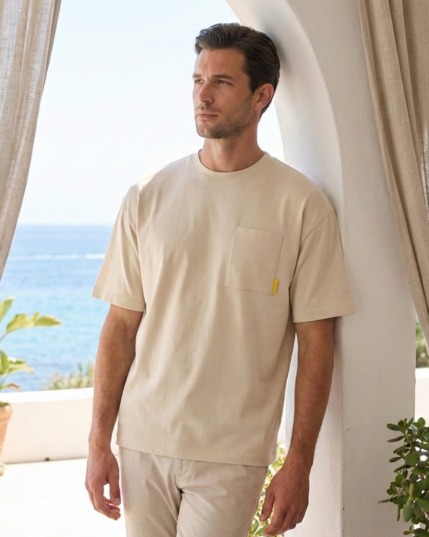 Model in a beige oversized t-shirt standing next to a pillar